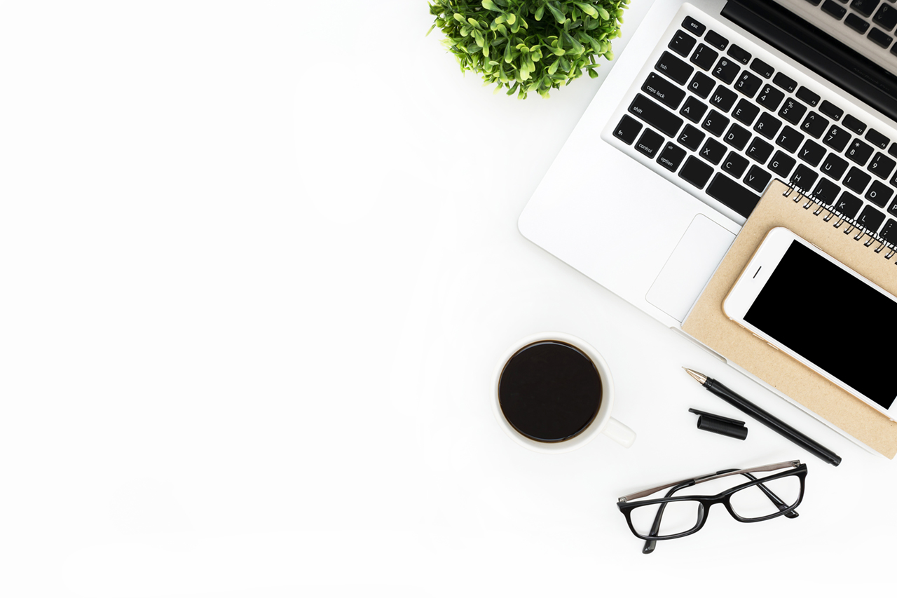 Modern white office desk table with laptop computer, smartphone with black screen over a notebook and cup of coffee. Top view with copy space, flat lay.